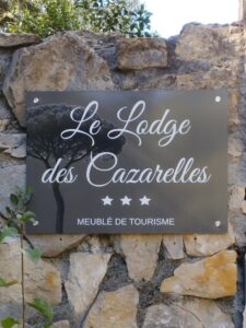 Enseigne d'entrée du Lodge des Cazarelles sur mur en pierre affichant le classement officiel 3 étoiles.