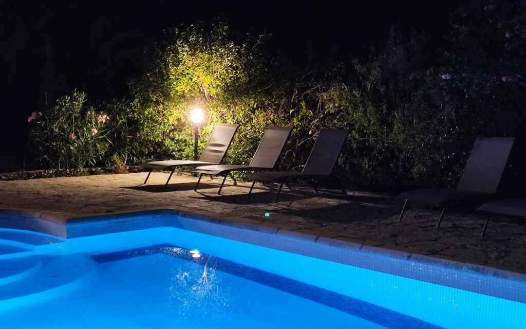 Piscine illuminée la nuit avec éclairage bleu pour une ambiance romantique et des baignades nocturnes.