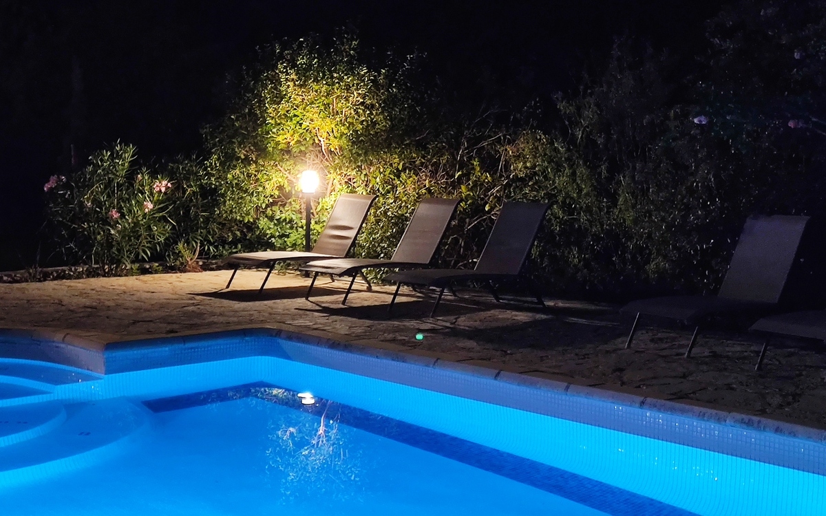 Piscine illuminée la nuit avec éclairage bleu pour une ambiance romantique et des baignades nocturnes.