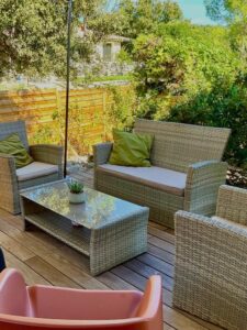 Espace détente extérieur avec canapé et fauteuils sur la terrasse en bois du lodge, idéal pour l'apéro.