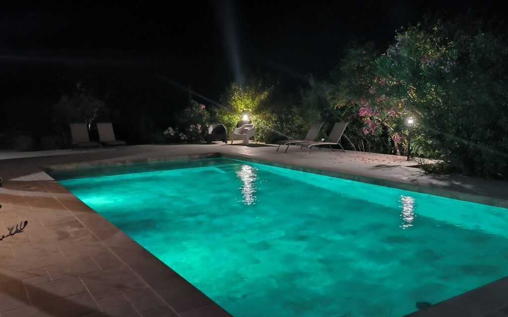 Piscine illuminée la nuit avec éclairage bleu pour une ambiance romantique et des baignades nocturnes.